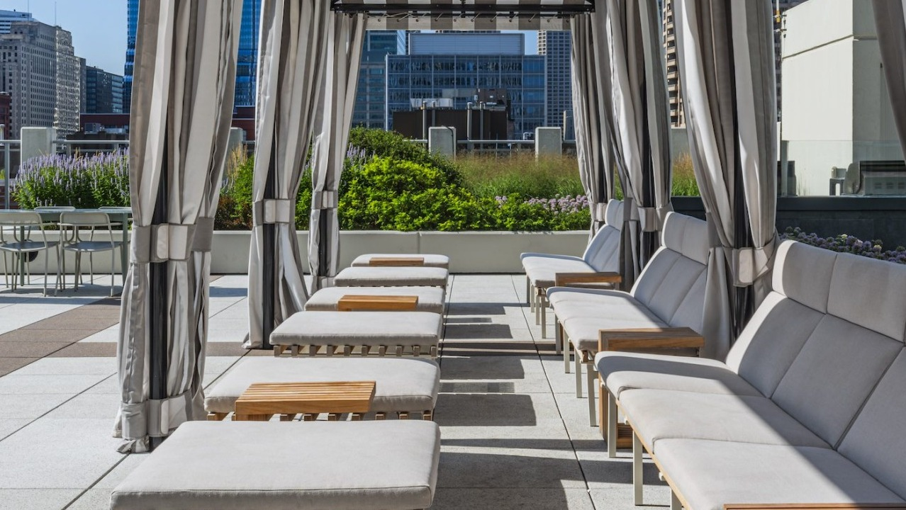 Rooftop cabanas with cushioned loungers, striped drapes, and skyline views at Alta at K Station, creating a relaxing outdoor lounge for Chicago residents