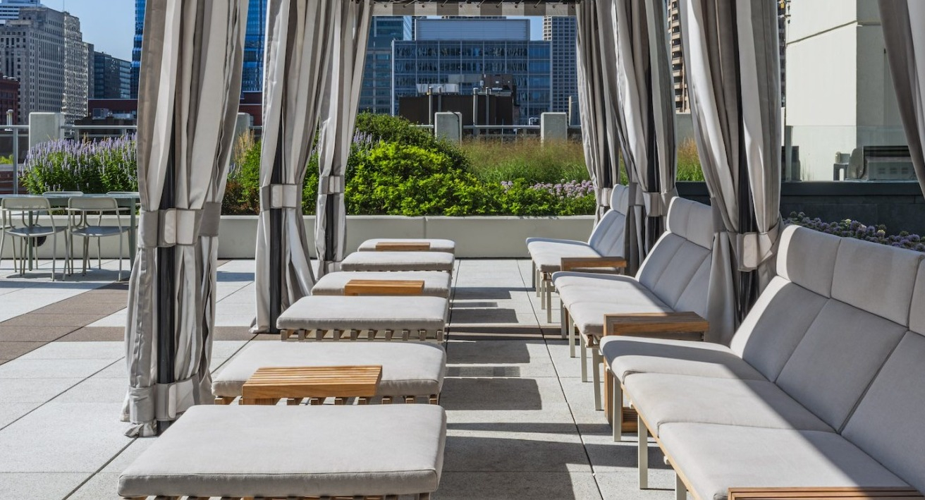 Rooftop cabanas with cushioned loungers, striped drapes, and skyline views at Alta at K Station, creating a relaxing outdoor lounge for Chicago residents
