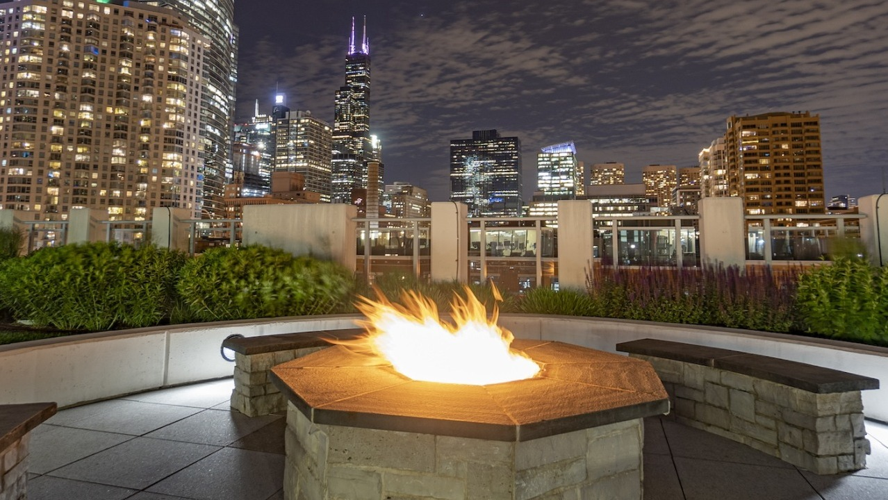 Rooftop firepit at Alta at K Station overlooking Chicago skyline at night, with modern seating and city lights creating a vibrant backdrop