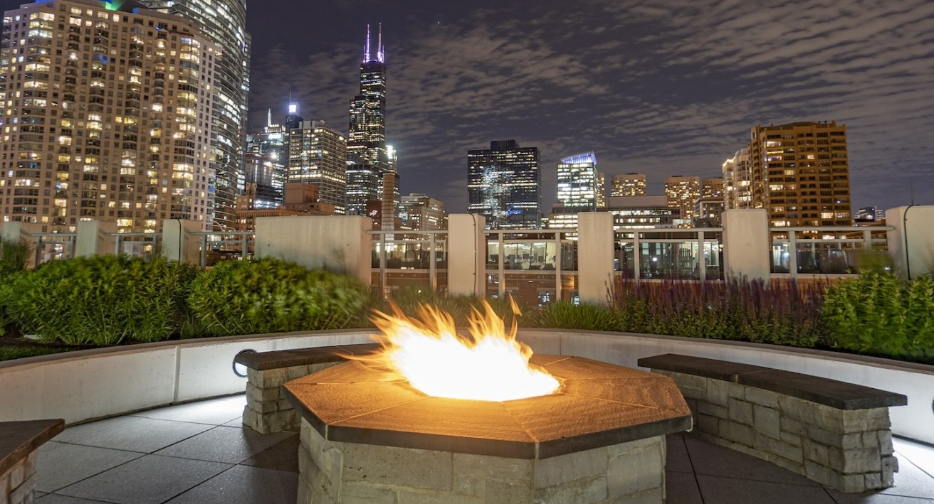 Rooftop firepit at Alta at K Station overlooking Chicago skyline at night, with modern seating and city lights creating a vibrant backdrop