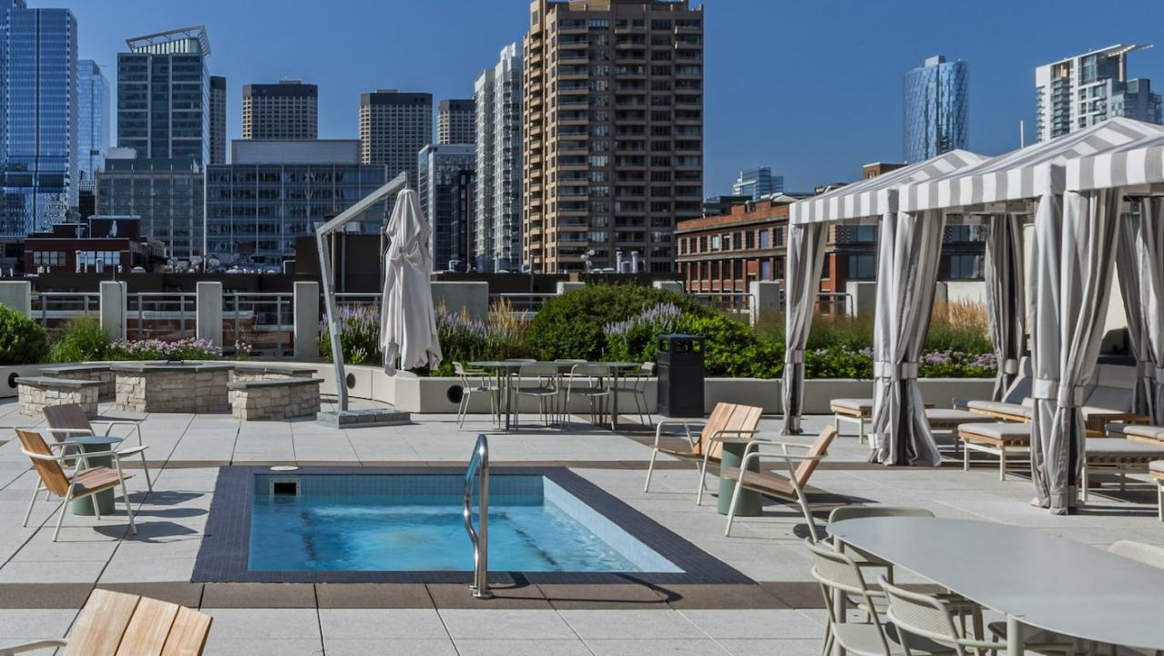 Expansive rooftop sundeck at Alta at K Station featuring a hot tub, shaded cabanas, fire pit, and outdoor dining areas overlooking downtown Chicago