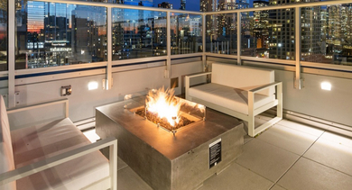 Rooftop lounge at AMLI 808 in Chicago with a cozy fire pit, cushioned seating, and skyline views—perfect for evening hangouts and weekend relaxation