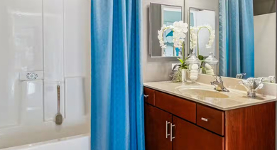 Contemporary bathroom at AMLI 900 with tub-shower combo, blue curtains, wide vanity, mirror, and modern gray walls for a clean look in Chicago
