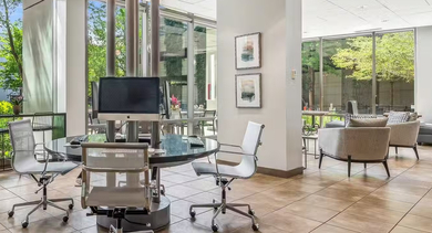 Light-filled business center at AMLI 900 with computer workstations, café seating, floor-to-ceiling windows, and a coffee bar for remote work in Chicago