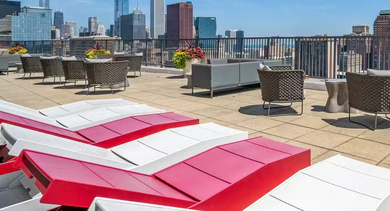 Rooftop sundeck at AMLI 900 with lounge chairs, seating areas, planters, and spectacular city and lake views of downtown Chicago on a bright, sunny day