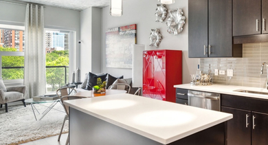 Open-plan kitchen with an island, dark cabinetry, and stainless steel appliances, overlooking the living area at AMLI Lofts