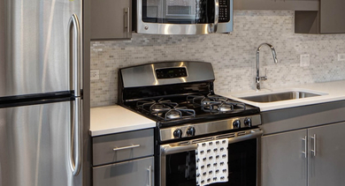 Sleek kitchen with gray cabinets, white countertops, and stainless steel appliances including a large fridge at AMLI Lofts