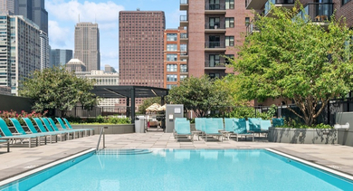 Sparkling outdoor swimming pool surrounded by teal lounge chairs and city skyline views at AMLI Lofts in Chicago