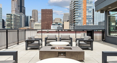 Outdoor rooftop patio with modern seating and a fire pit, offering stunning views of the Chicago skyline at AMLI Lofts