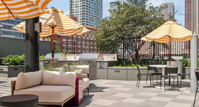 Rooftop lounge with comfortable seating, dining tables, grilling stations, and city views at AMLI Lofts in Chicago