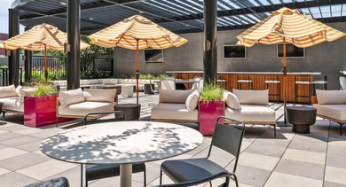 Expansive rooftop lounge with comfortable seating, dining tables, and large striped umbrellas at AMLI Lofts in Chicago
