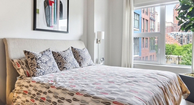 Spacious bedroom with a comfortable bed, bedside tables, and a large window providing ample natural light at AMLI Lofts