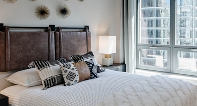 Cozy bedroom at AMLI River North, featuring a comfortable bed, elegant decor, and a picturesque Chicago cityscape from the window