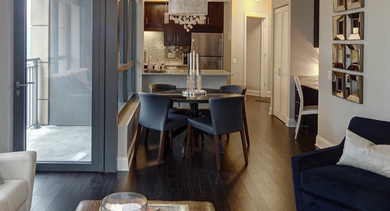 Combined dining and living area at AMLI River North, showcasing modern furniture, elegant lighting, and rich hardwood floors