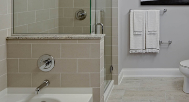 Modern bathroom at AMLI River North featuring a clean design, spacious tub, glass-enclosed shower, and a large vanity.