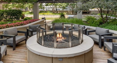 Inviting outdoor fire pit lounge area at AMLI River North, surrounded by lush greenery and comfortable seating