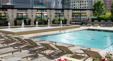 Luxurious rooftop swimming pool at AMLI River North, surrounded by lounge chairs, cabanas, and decorative fountains