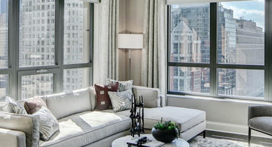 Spacious living room at AMLI River North, featuring modern furniture, large windows, and a stunning Chicago city view