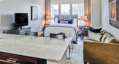 Open-concept studio apartment at AMLI River North, featuring a integrated kitchen, living area, and a comfortable bedroom space