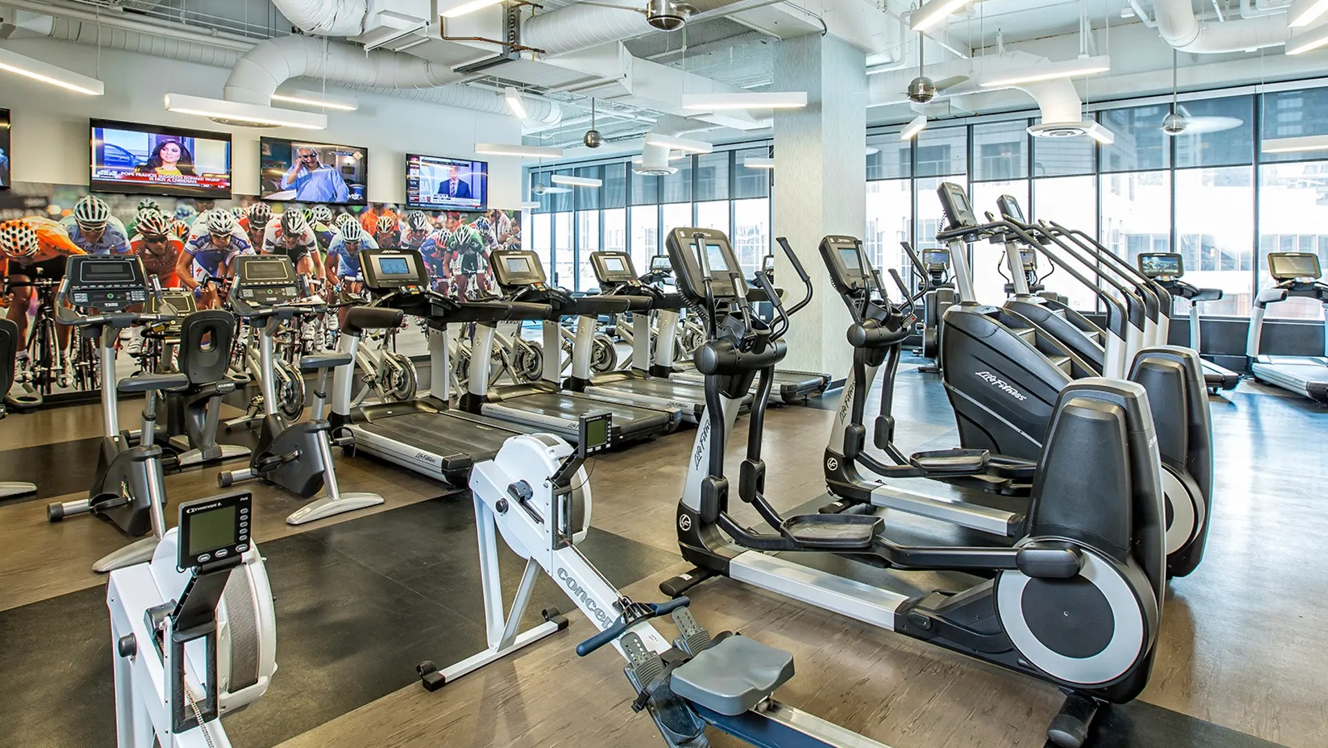 Modern fitness center with treadmills, bikes, row machines, and bright windows at Aqua at Lakeshore East Apartments in downtown Chicago