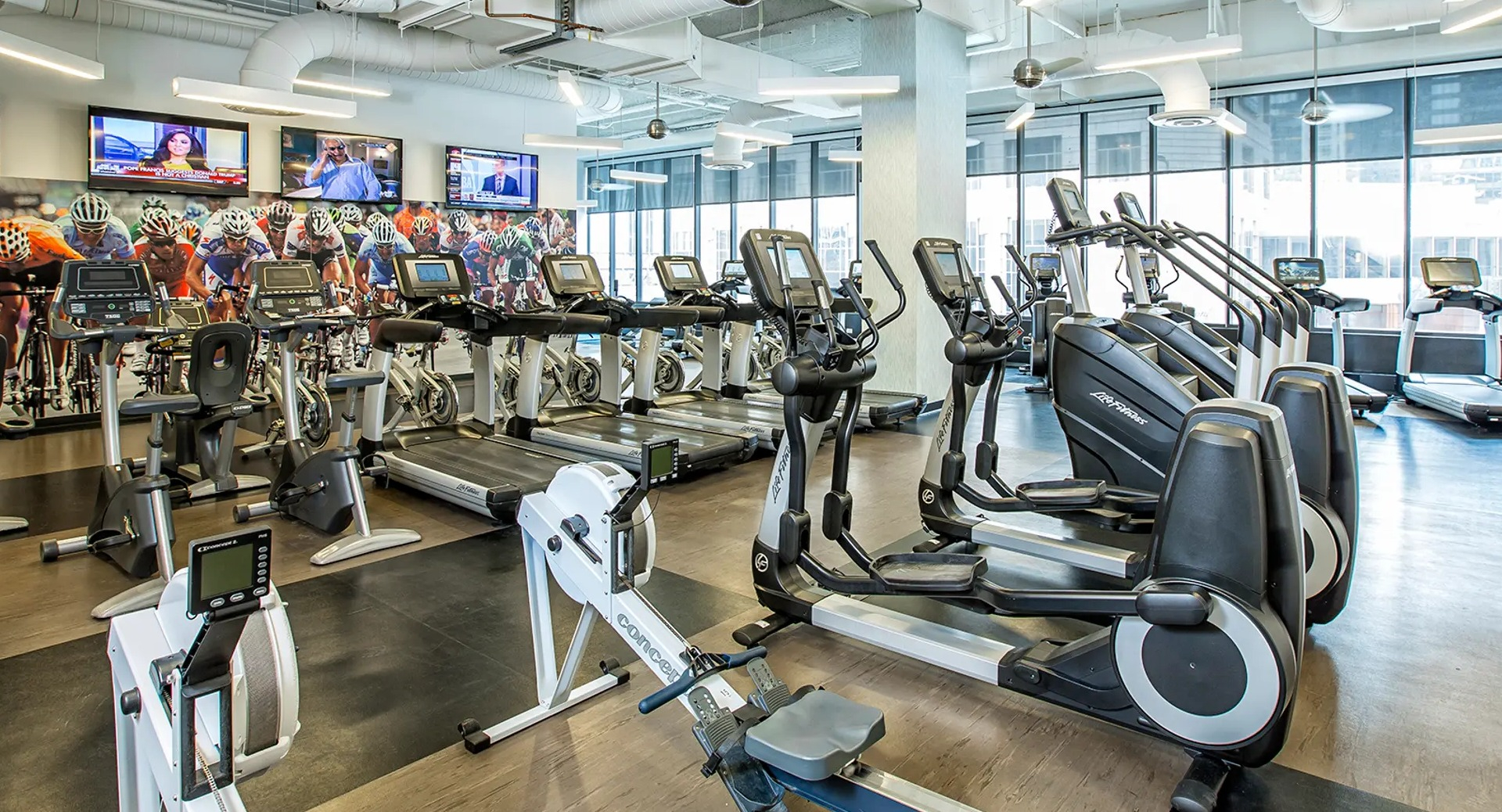 Modern fitness center with treadmills, bikes, row machines, and bright windows at Aqua at Lakeshore East Apartments in downtown Chicago
