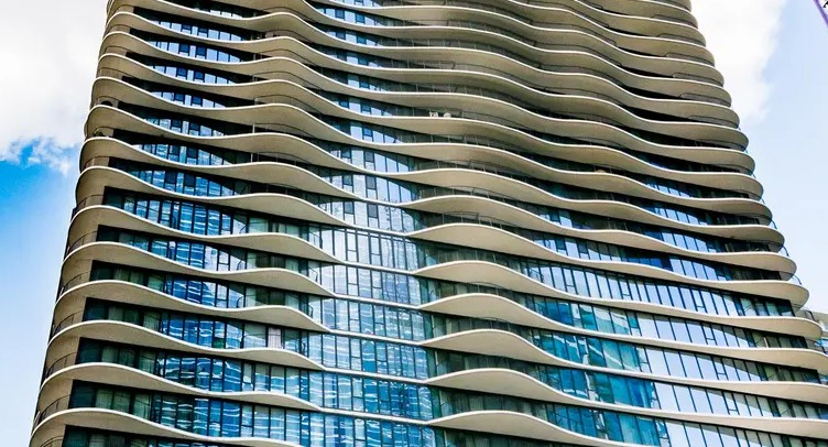 Iconic Aqua at Lakeshore East Apartments tower with signature wave-like balconies rising over downtown Chicago skyline