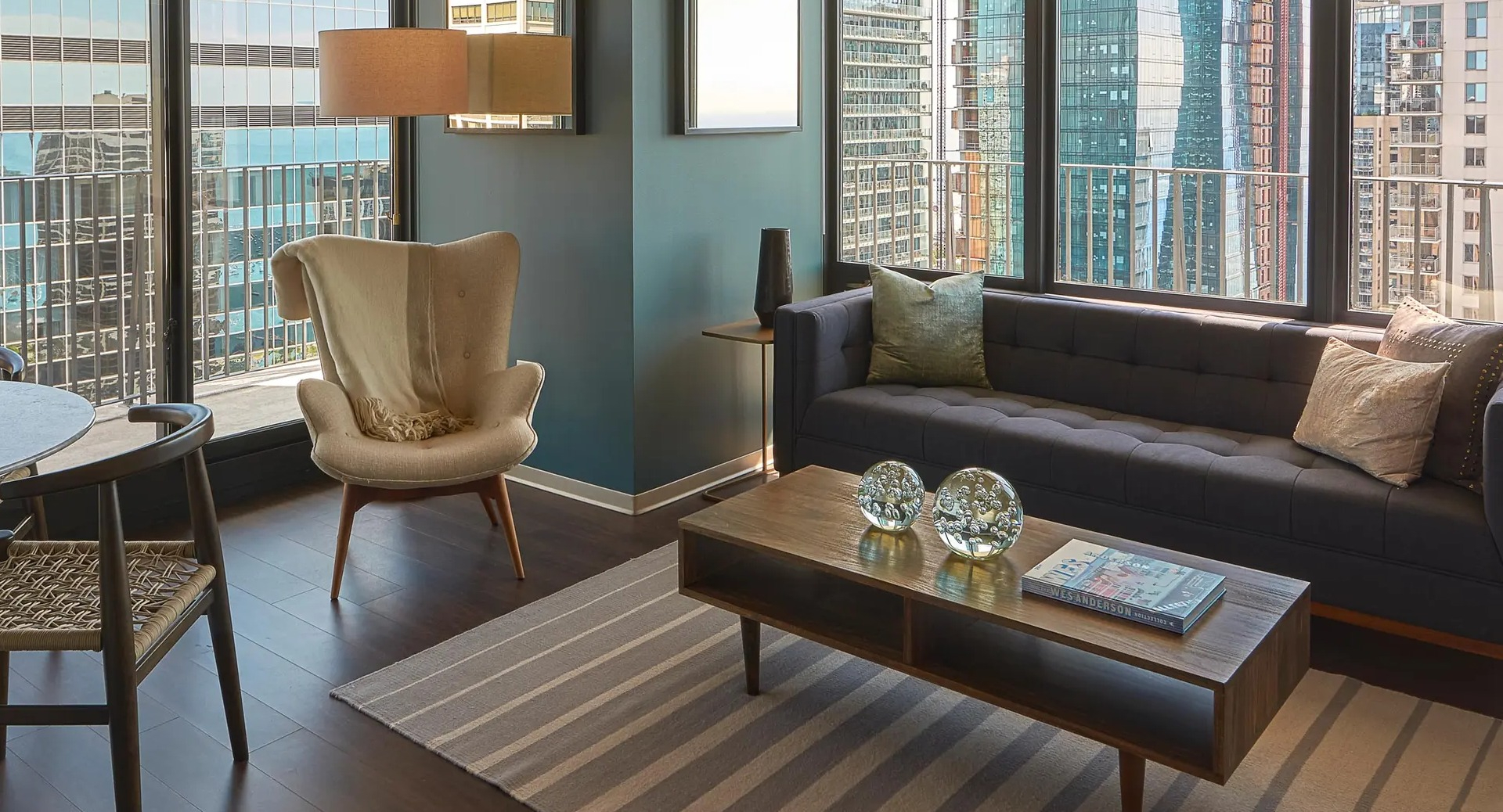 Cozy living room with modern sofa, accent chair, coffee table, and floor-to-ceiling windows overlooking downtown Chicago at Aqua at Lakeshore East Apartments