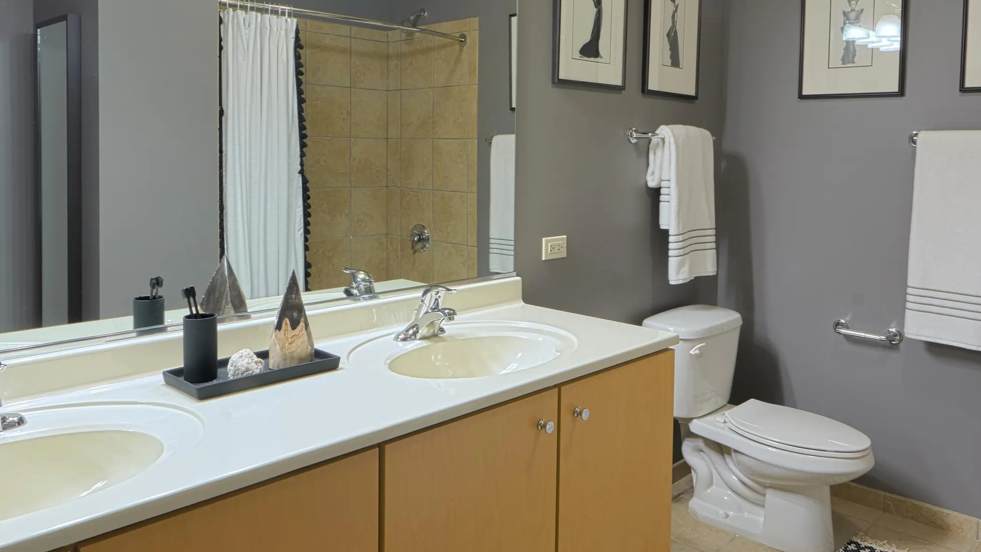 Spacious bathroom with double vanity, framed art, neutral tile, and hotel-style linens at Aqua at Lakeshore East Apartments in downtown Chicago