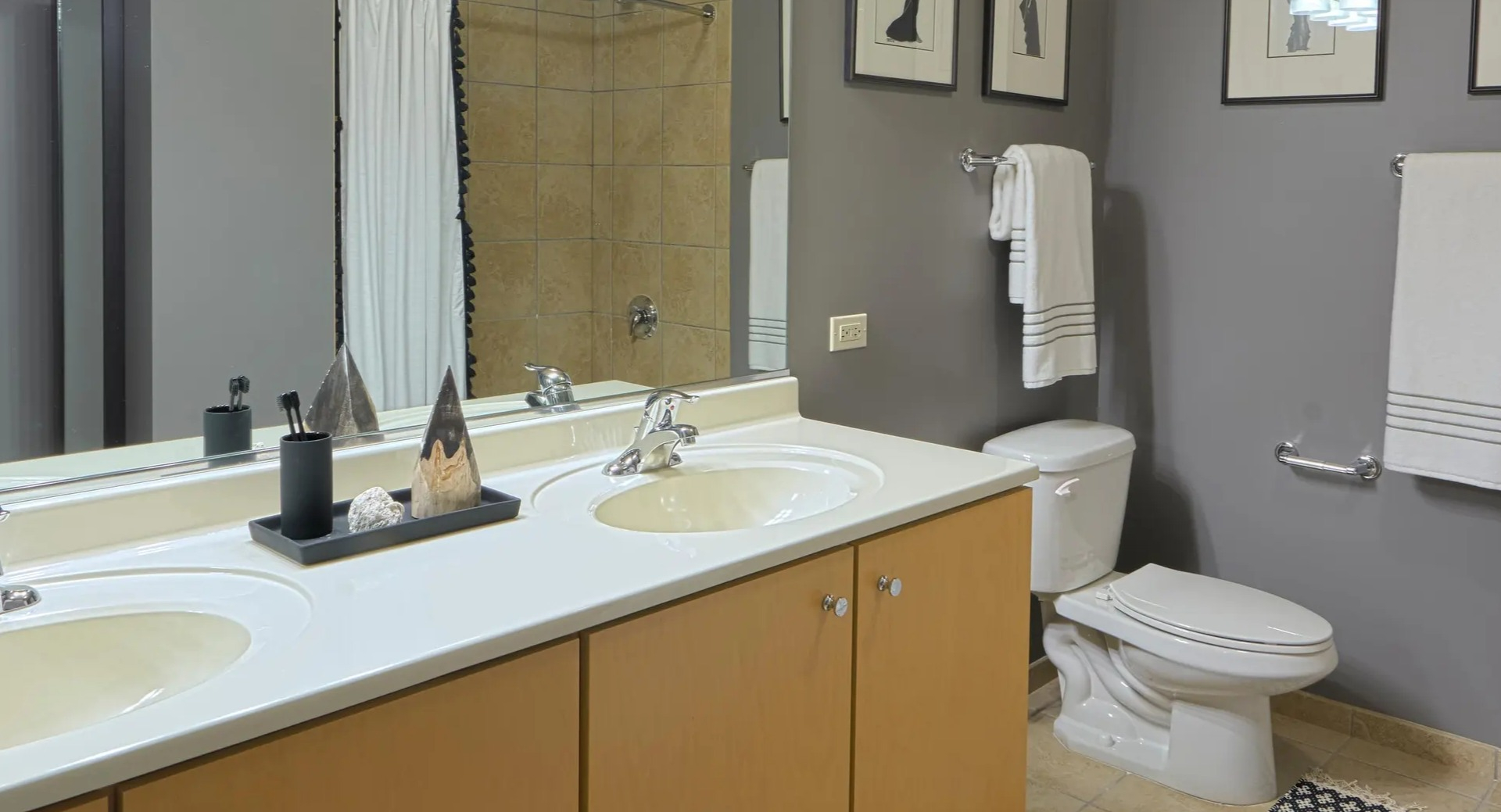 Spacious bathroom with double vanity, framed art, neutral tile, and hotel-style linens at Aqua at Lakeshore East Apartments in downtown Chicago