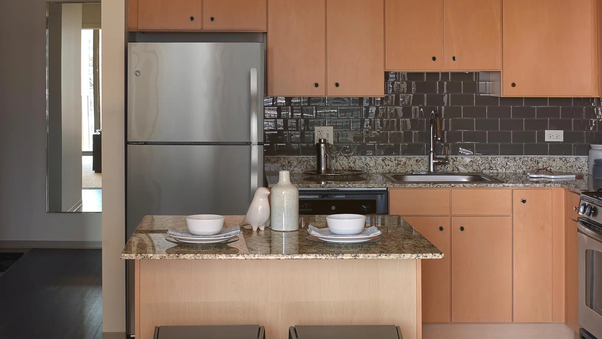 Contemporary kitchen with granite island seating, stainless appliances, and glossy subway tile backsplash at Aqua at Lakeshore East Apartments in Chicago