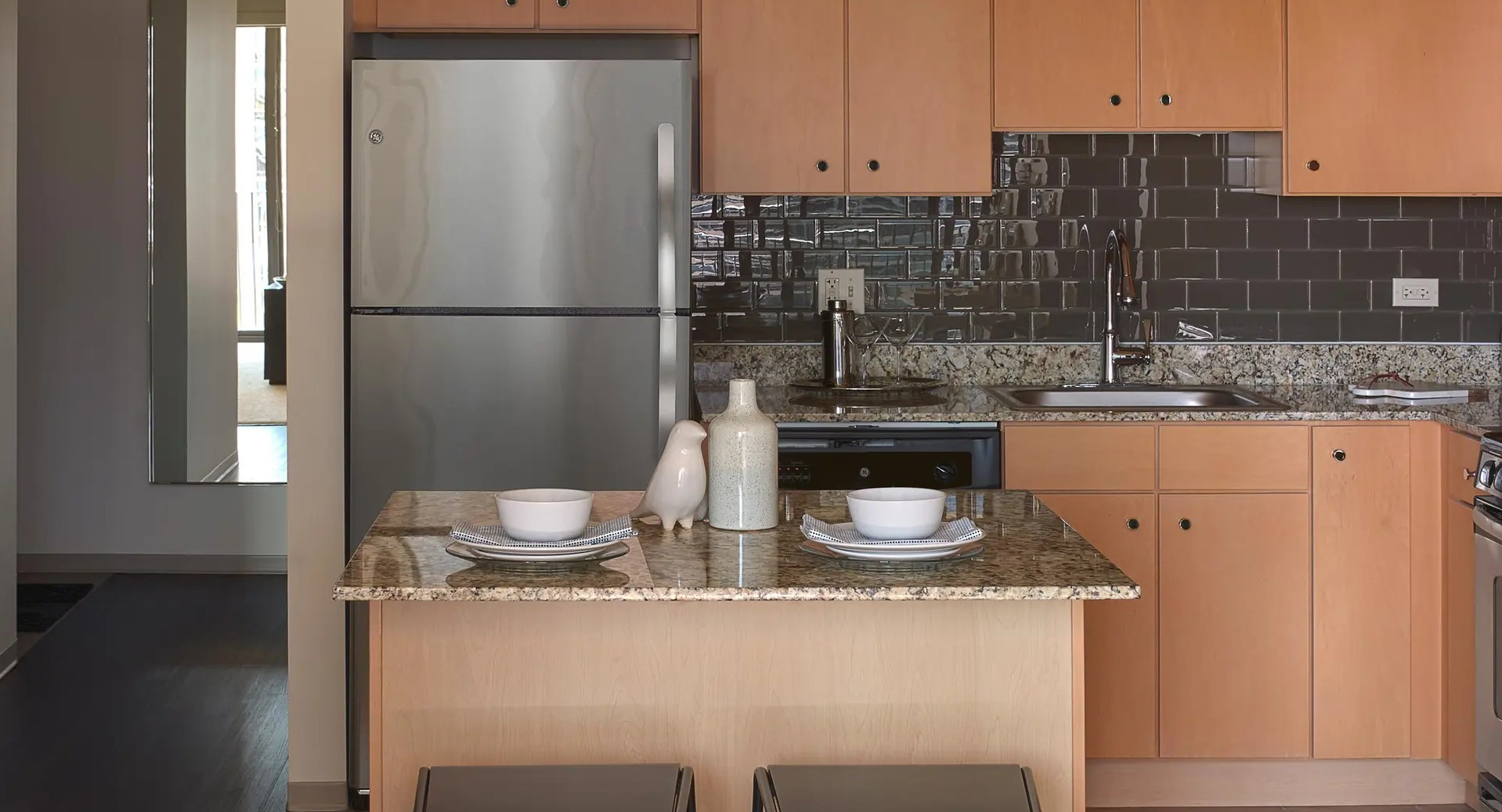 Contemporary kitchen with granite island seating, stainless appliances, and glossy subway tile backsplash at Aqua at Lakeshore East Apartments in Chicago
