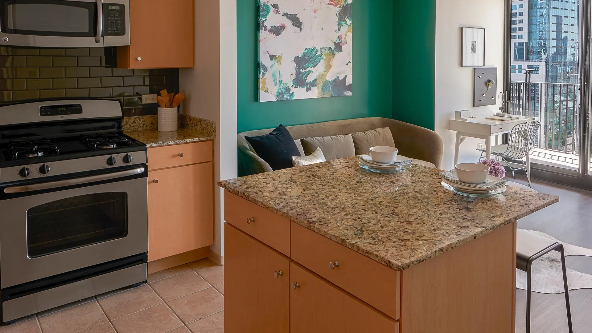 Open-concept layout with granite island kitchen, lounge nook, and balcony doors bringing in Chicago skyline light at Aqua at Lakeshore East Apartments