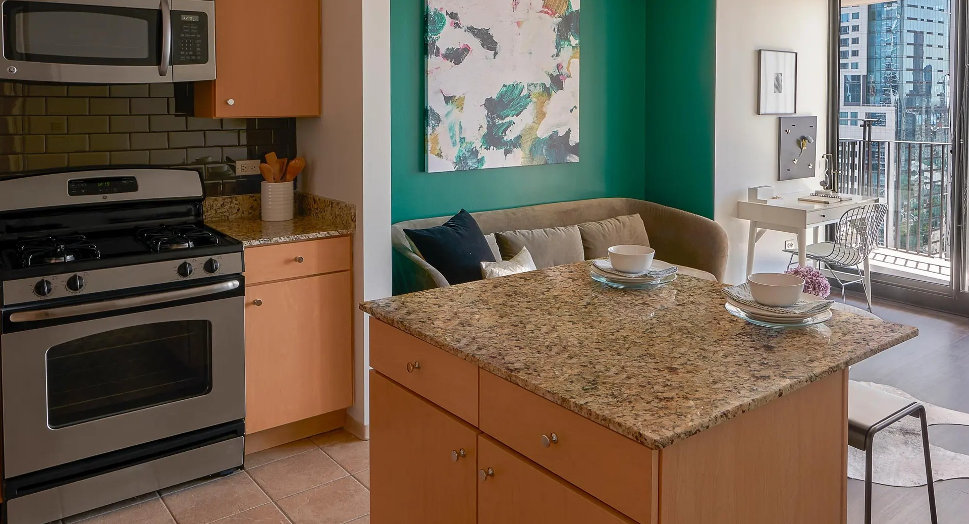 Open-concept layout with granite island kitchen, lounge nook, and balcony doors bringing in Chicago skyline light at Aqua at Lakeshore East Apartments