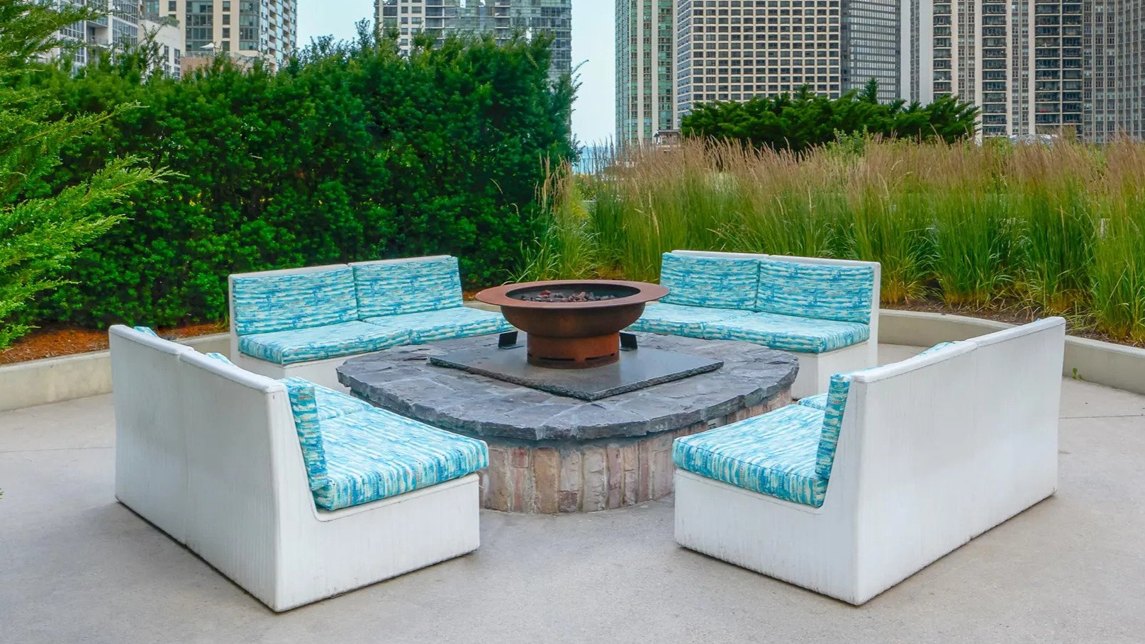 Outdoor fire pit lounge with modern seating, city high-rise views, and lush greenery at Aqua at Lakeshore East Apartments in Chicago
