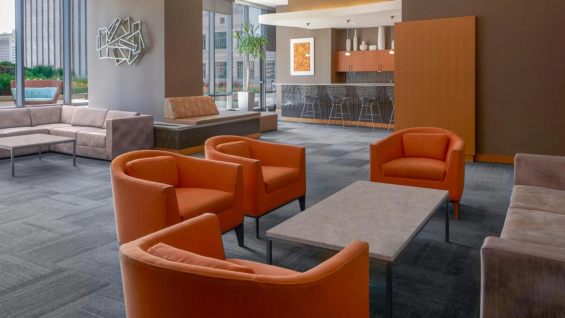 Party suite featuring bold orange seating, lounge area, and bar space with city views at Aqua at Lakeshore East Apartments in Chicago