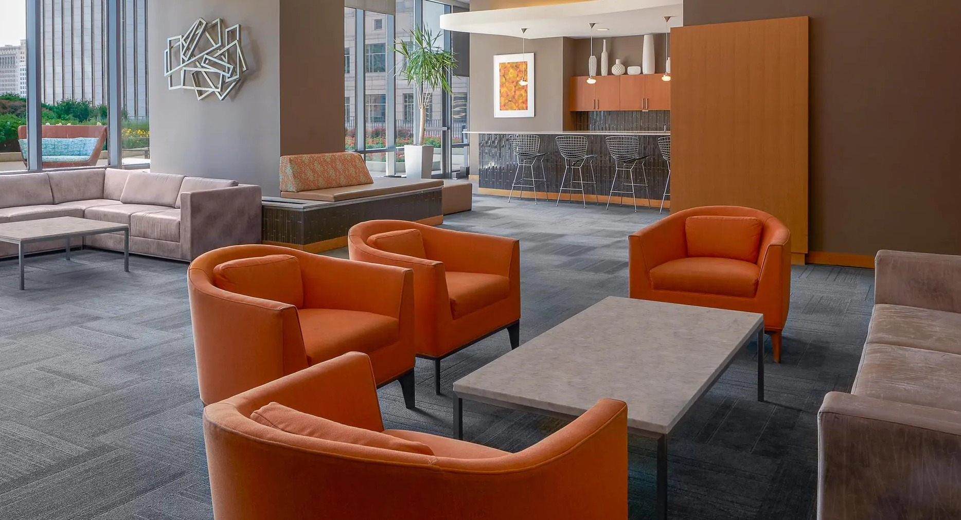 Party suite featuring bold orange seating, lounge area, and bar space with city views at Aqua at Lakeshore East Apartments in Chicago