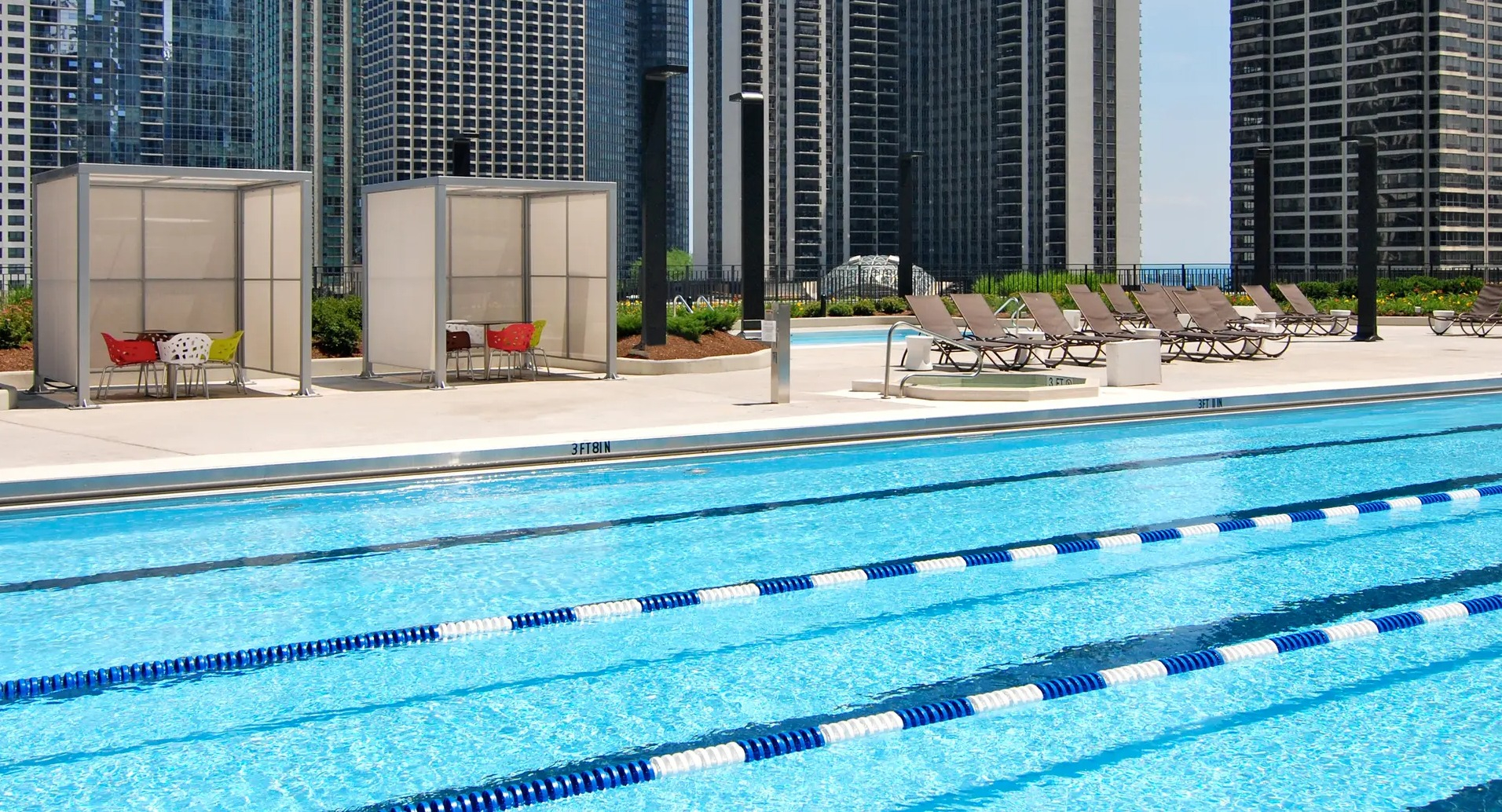 Outdoor pool deck with lap lanes, cabanas, and lounge chairs set against Chicago high-rises at Aqua at Lakeshore East Apartments in Lakeshore East