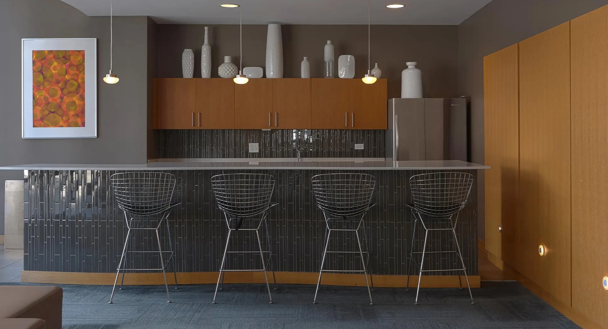 Modern private bar area with counter seating, pendant lighting, and sleek finishes at Aqua at Lakeshore East Apartments in Chicago