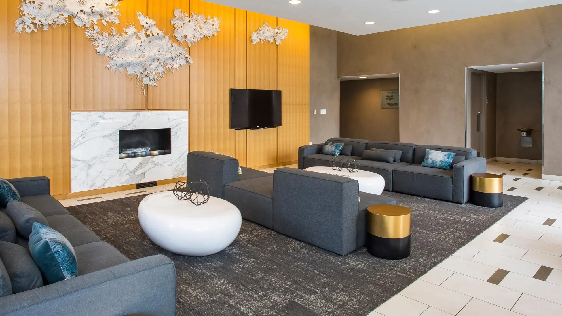 Elegant resident lounge with modern sofas, marble fireplace, wall art, and cozy seating at Aqua at Lakeshore East Apartments in Chicago