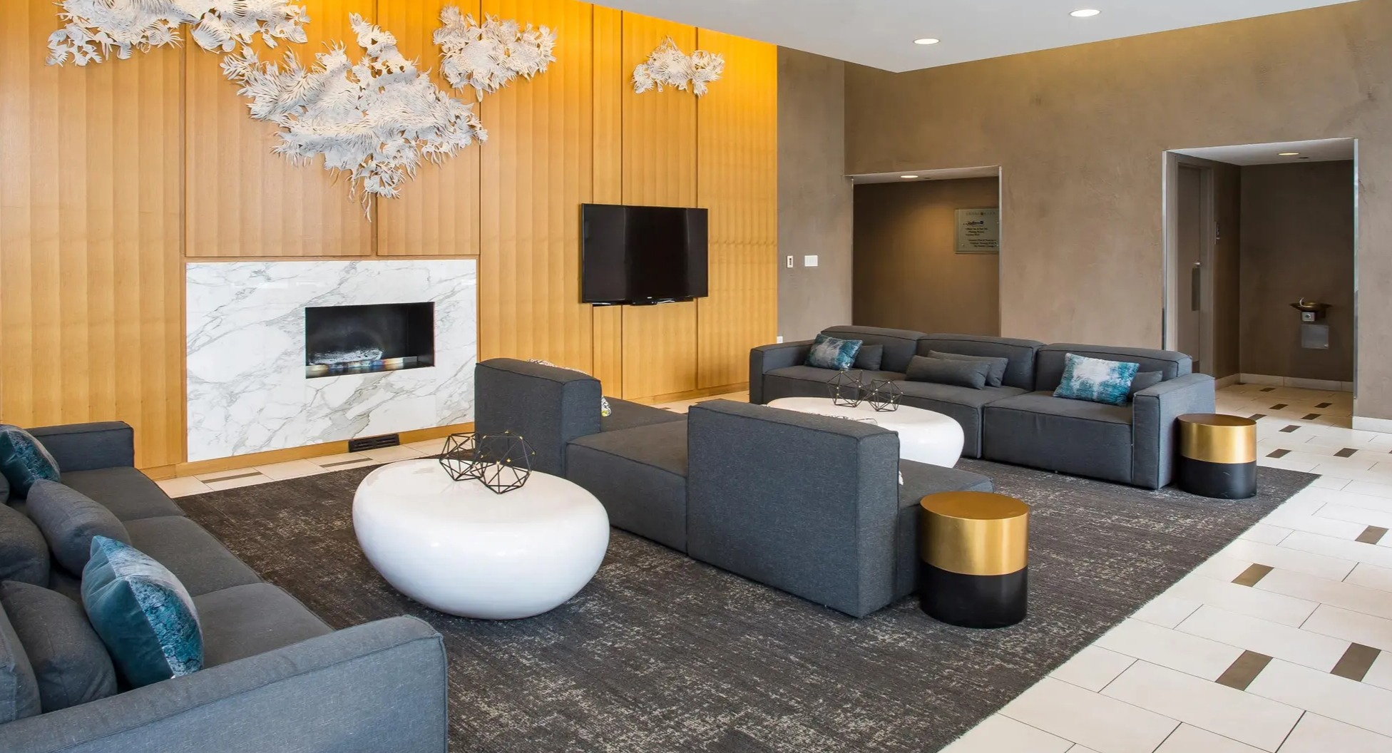 Elegant resident lounge with modern sofas, marble fireplace, wall art, and cozy seating at Aqua at Lakeshore East Apartments in Chicago