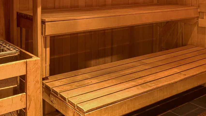 Warm wooden sauna room with bench seating and heater for resident relaxation at Aqua at Lakeshore East Apartments in Chicago