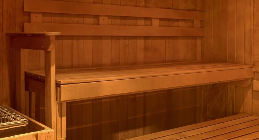Warm wooden sauna room with bench seating and heater for resident relaxation at Aqua at Lakeshore East Apartments in Chicago