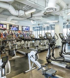 Fully equipped fitness center with cardio machines, cycling equipment, and large windows at Aqua at Lakeshore East