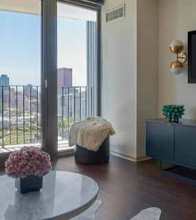 Contemporary living room with a mounted TV, modern furniture, and a balcony offering stunning views of the city at Aqua at Lakeshore East