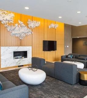 Modern lounge area with comfortable seating, a marble fireplace, and decorative wall art at Aqua at Lakeshore East