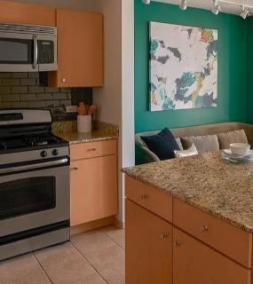 Modern kitchen with stainless steel appliances, an island countertop, and a cozy dining area at Aqua at Lakeshore East