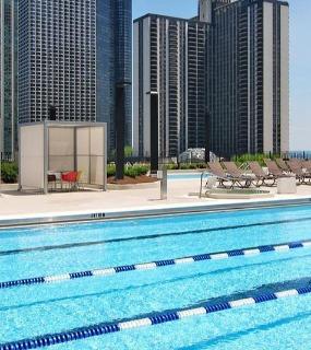 Outdoor pool with lounge chairs, cabanas, and stunning views of Chicago's skyscrapers at Aqua at Lakeshore East