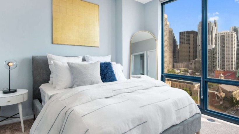 Cozy bedroom at Arkadia West Loop featuring a comfortable bed, stylish decor, and stunning city views