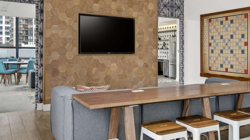 Inviting community lounge at Arkadia West Loop with a large TV, comfortable seating, and a Scrabble board
