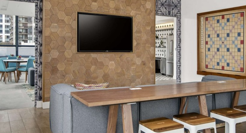 Inviting community lounge at Arkadia West Loop with a large TV, comfortable seating, and a Scrabble board